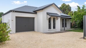 Une maison moderne à deux étages, dotée d’un garage, d’un porche couvert et d’une allée en gravier.
