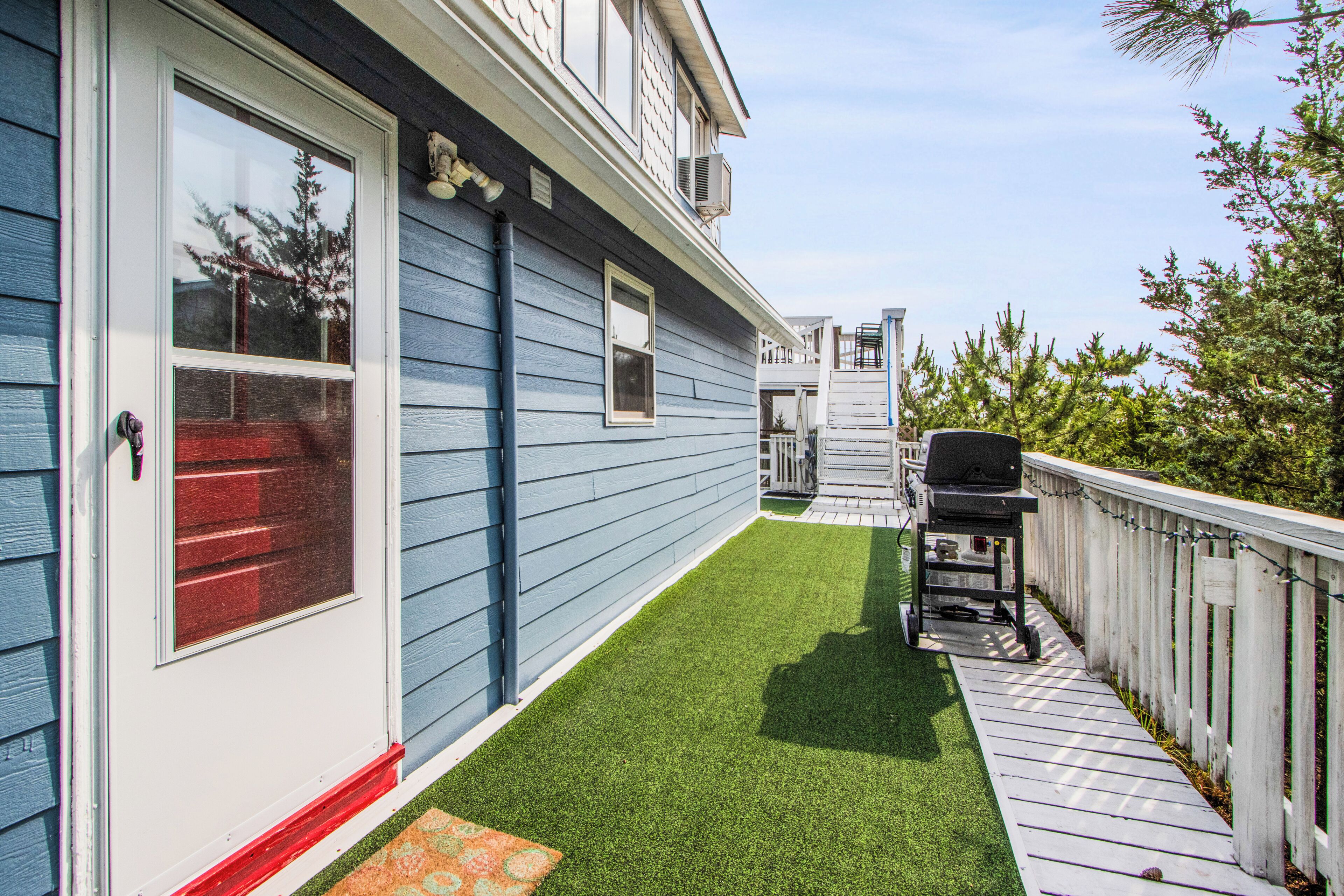 A residential backyard with a wooden deck, a barbecue grill, and a small shed.