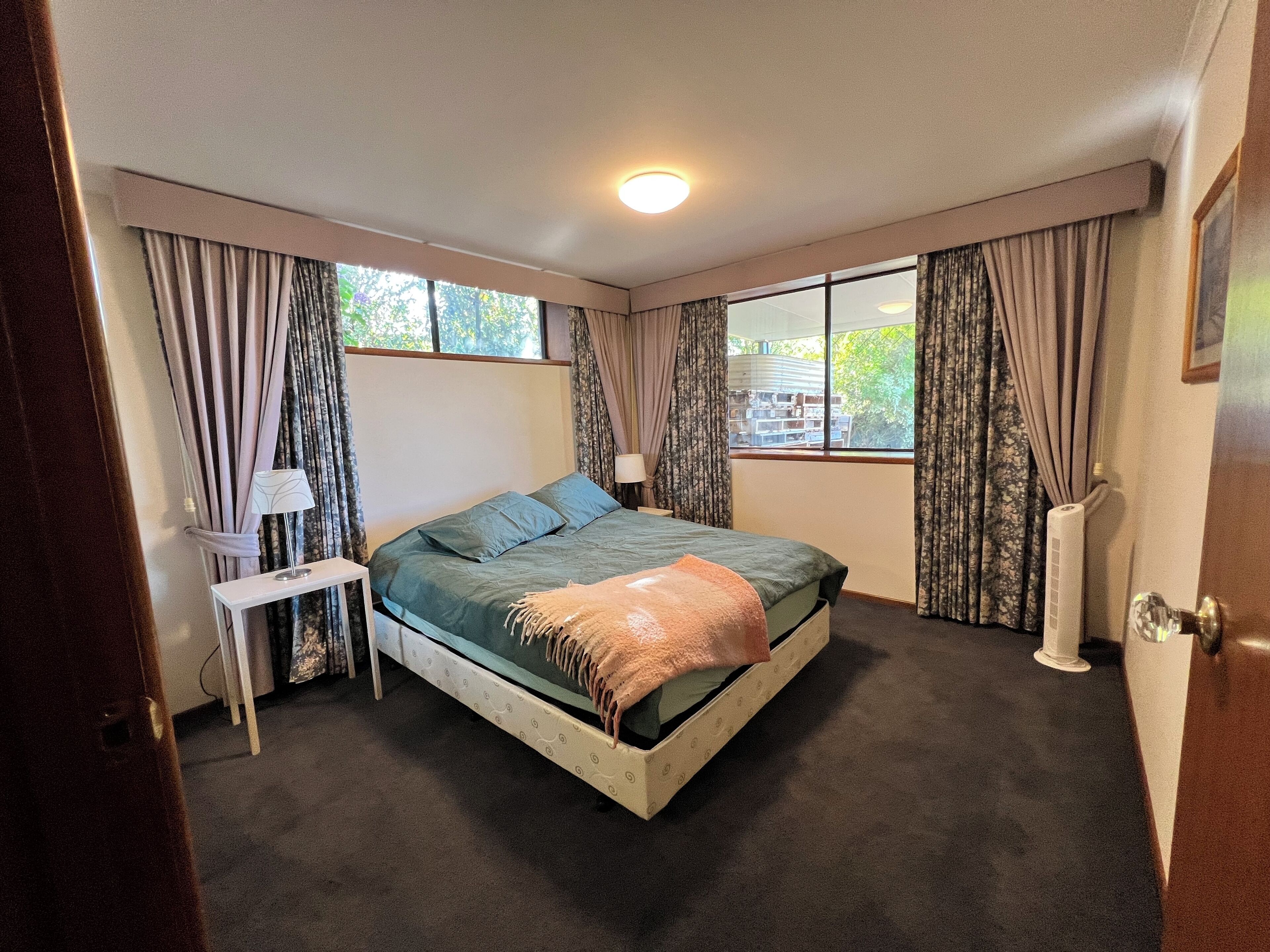 Une chambre à coucher avec un lit, des tables de chevet, une fenêtre et des rideaux.