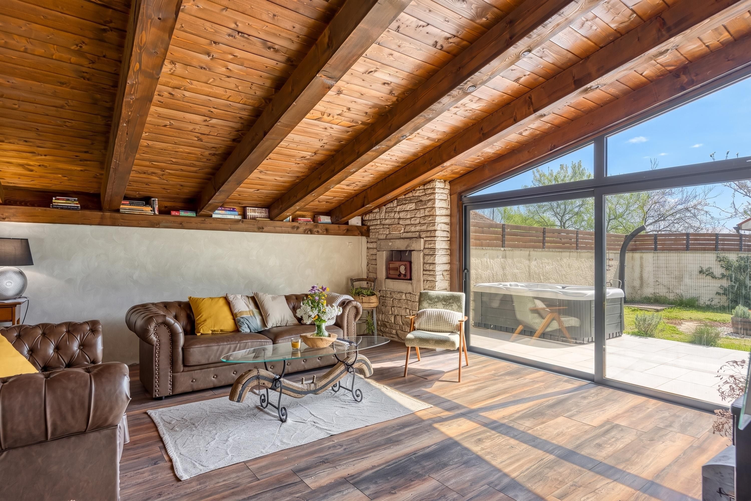 A spacious living area with a leather sofa, a glass coffee table, and a stone fireplace.