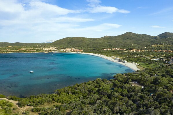 A coastal landscape with a beach, clear blue waters, and mountainous terrain in the background. - Marcos Home (Olbia)