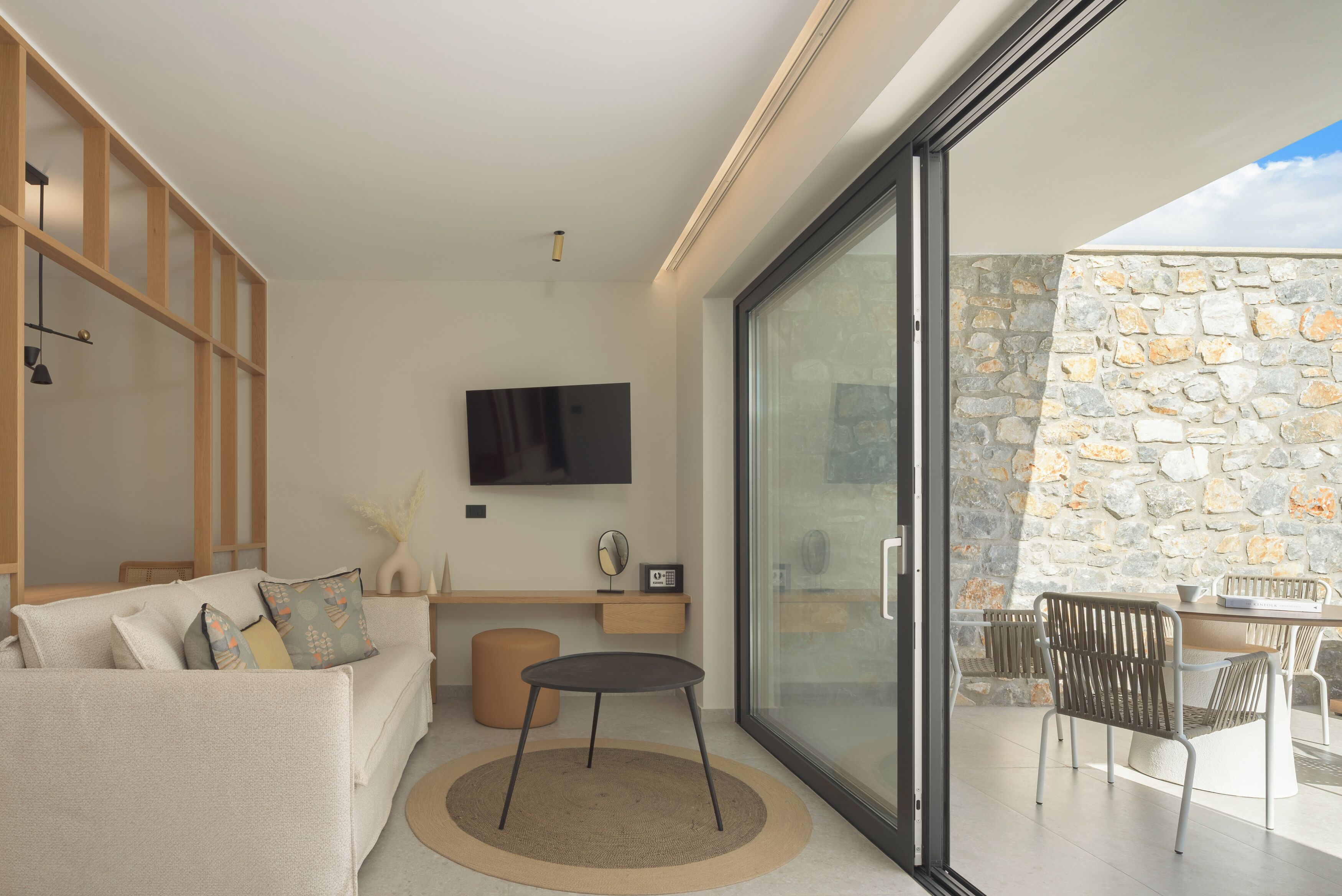 A modern living room with a sofa, a round table, and a TV mounted on the wall.