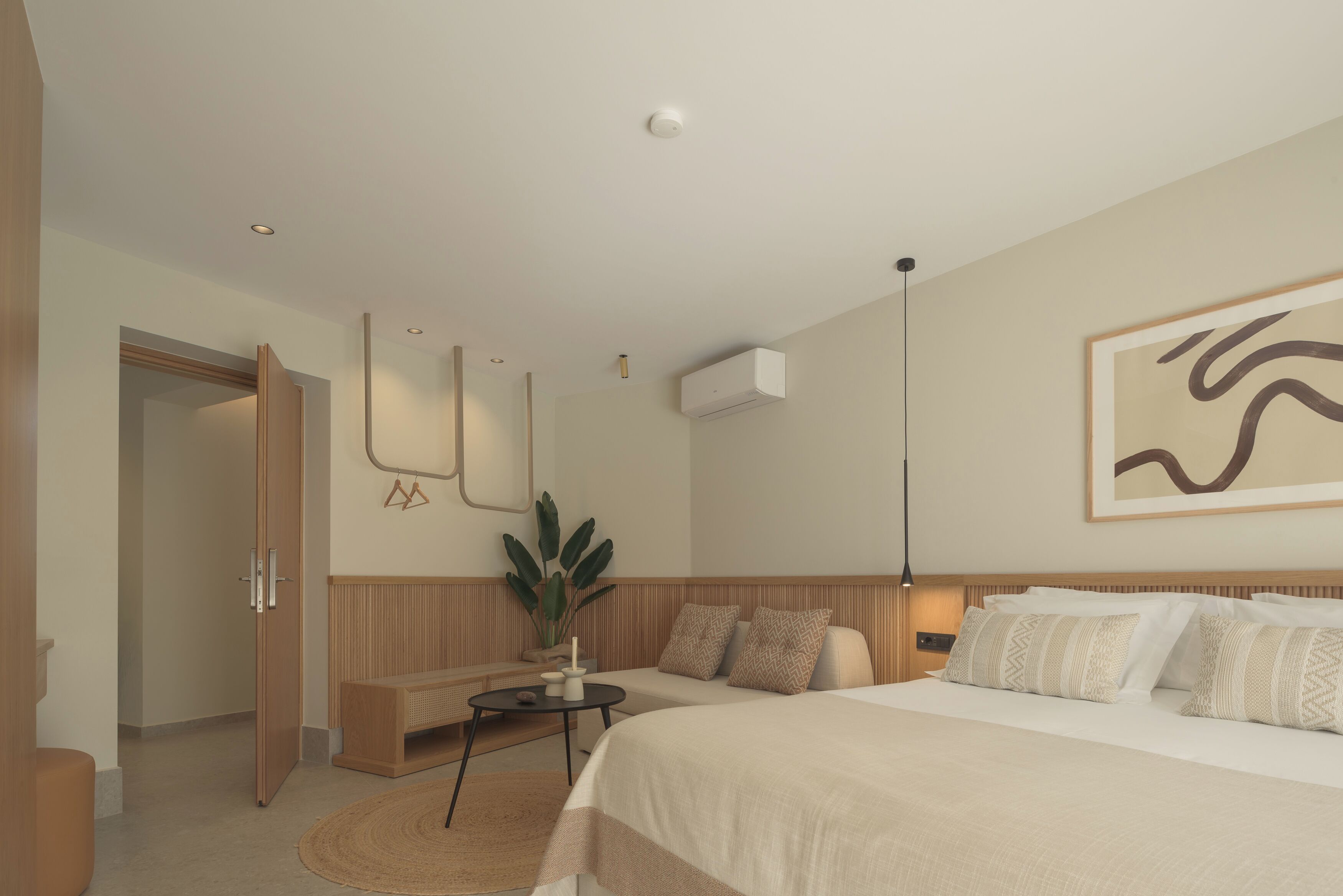 Ein modernes Schlafzimmer mit einem großen Bett, Nachttischen, einer Zimmerpflanze und einer Wandklimaanlage.