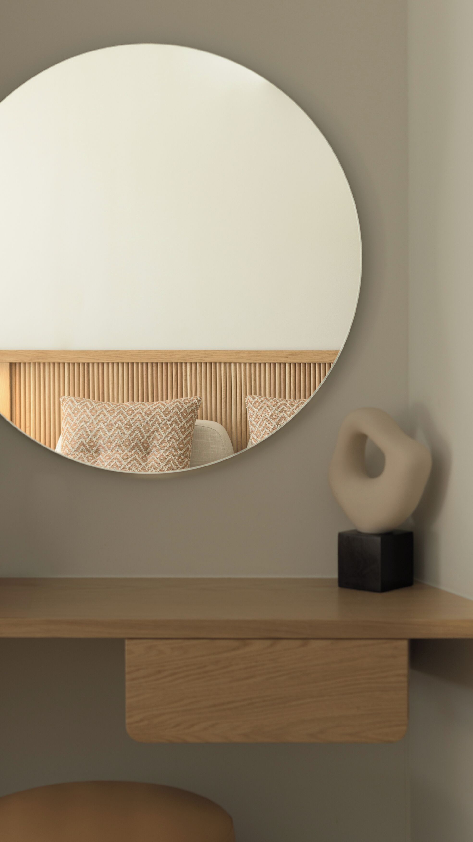 Una camera moderna con uno specchio rotondo, una testiera in legno e una scultura minimalista su una mensola di legno.