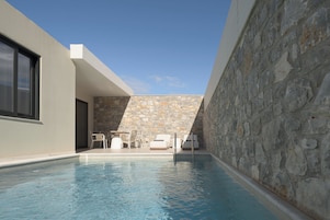 Un espace piscine moderne avec des murs en pierre et une piscine à l’eau d’un bleu cristallin.