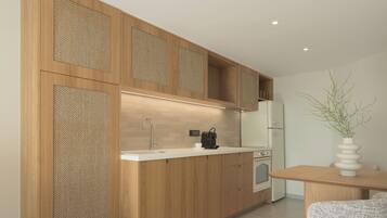 A modern kitchen with wooden cabinetry, a built-in sink, a coffee machine, and a dining area with a table and chair.