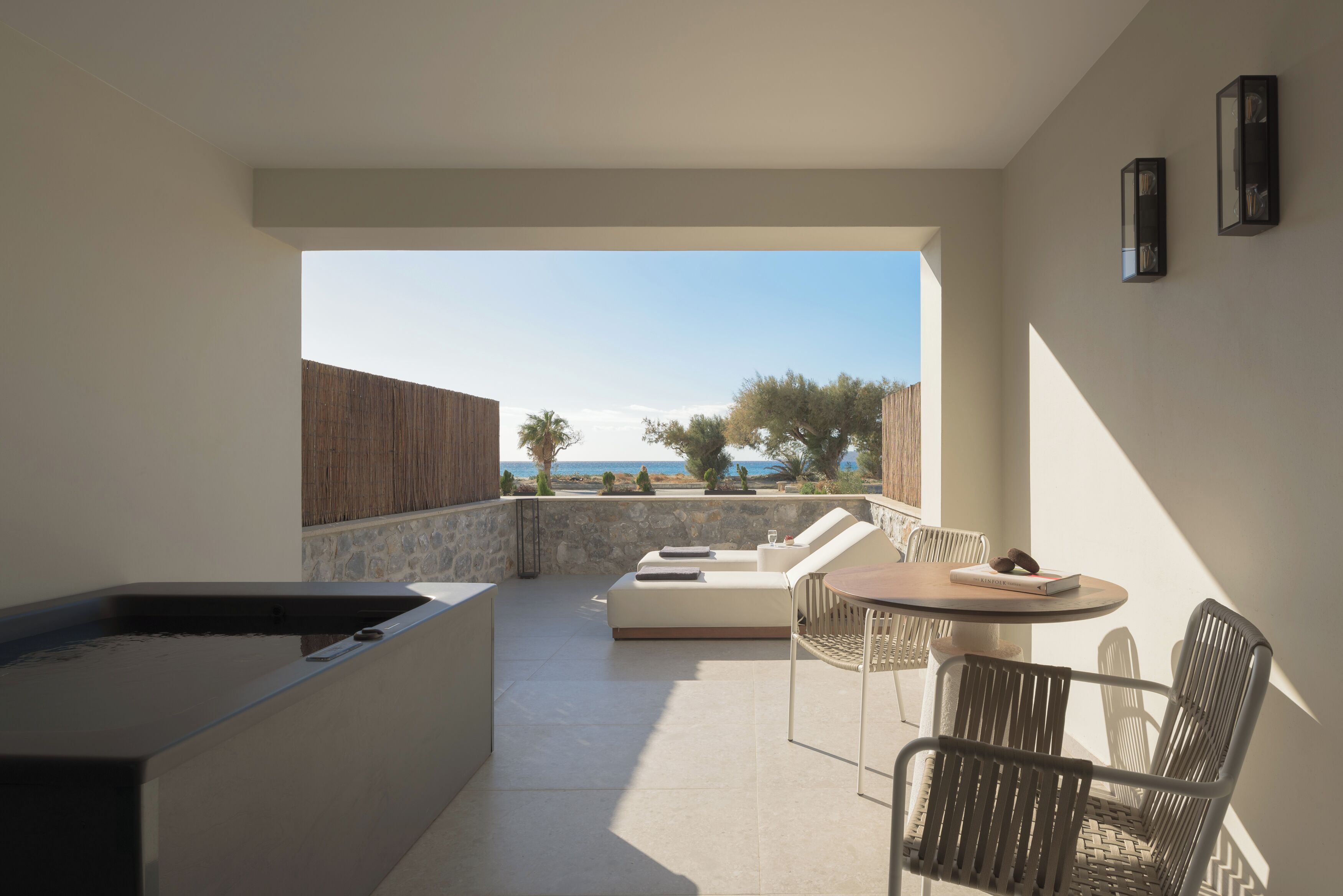 Een moderne buitenpatio met een stenen muur, een geïntegreerde keukenhoek en een zithoek gericht op een prachtig uitzicht.