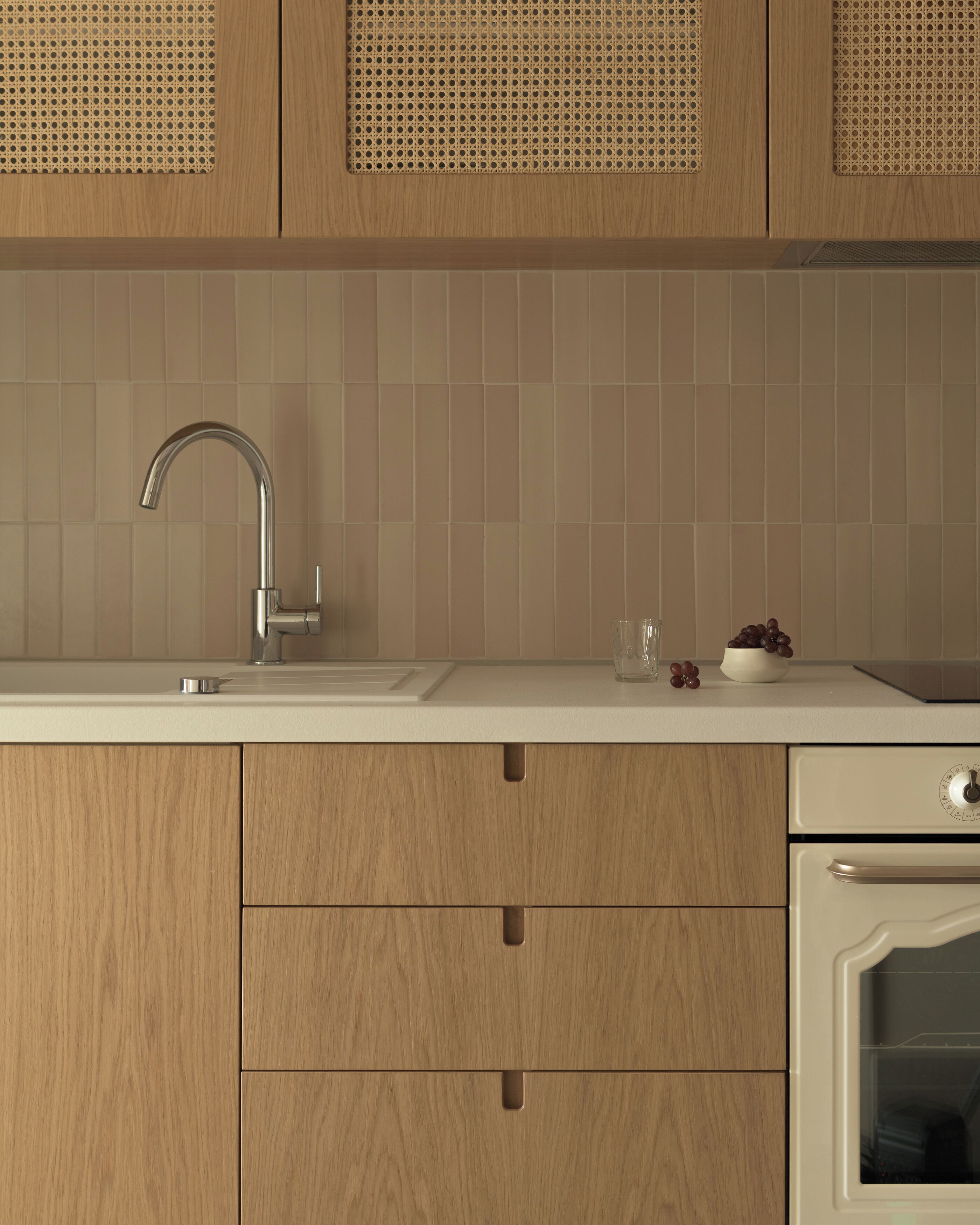 A kitchen with wooden cabinets, a white countertop, a stainless steel faucet, and a white oven.