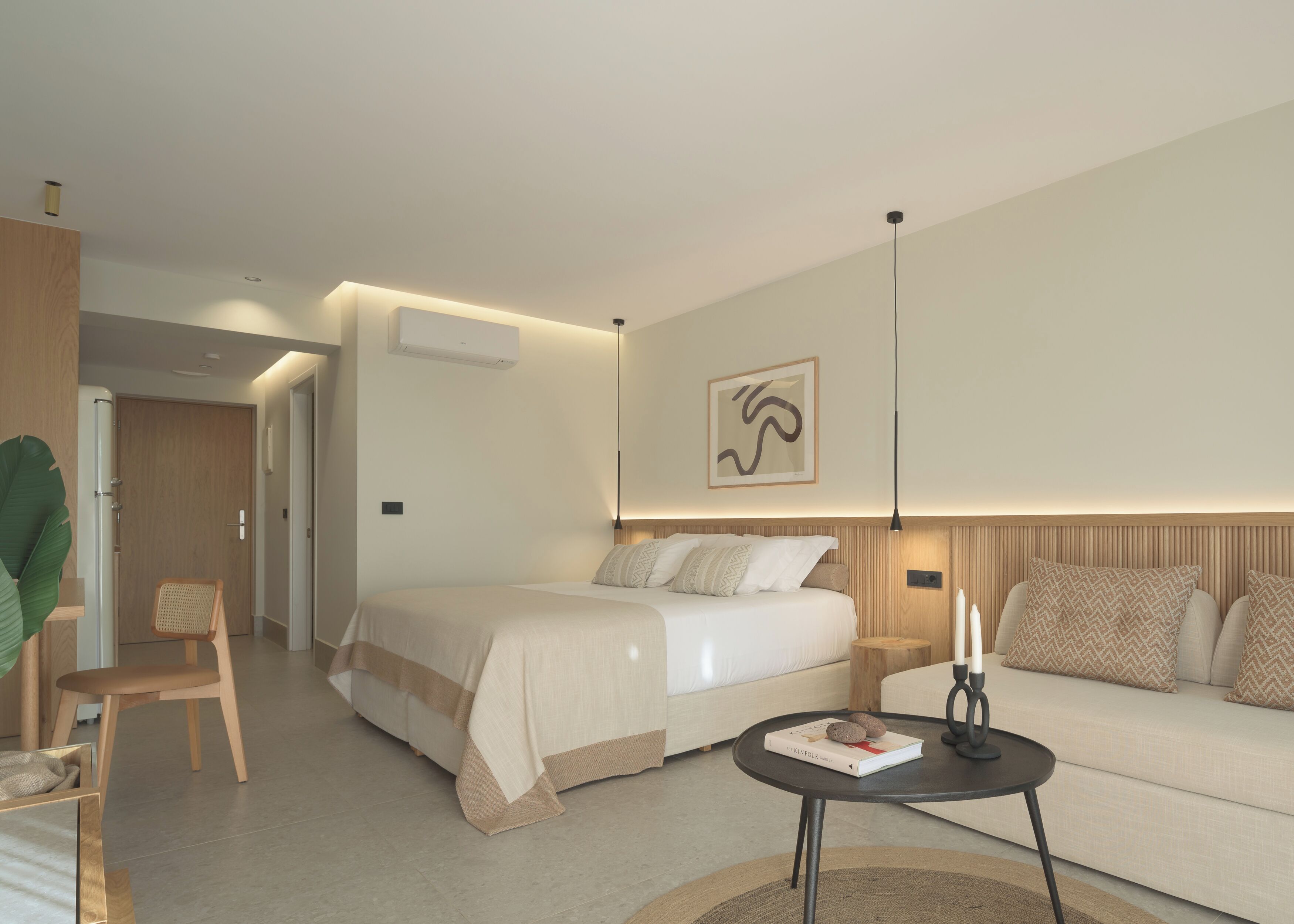 Ett modernt hotellrum med en stor säng, en soffa, ett litet bord och en stol.
