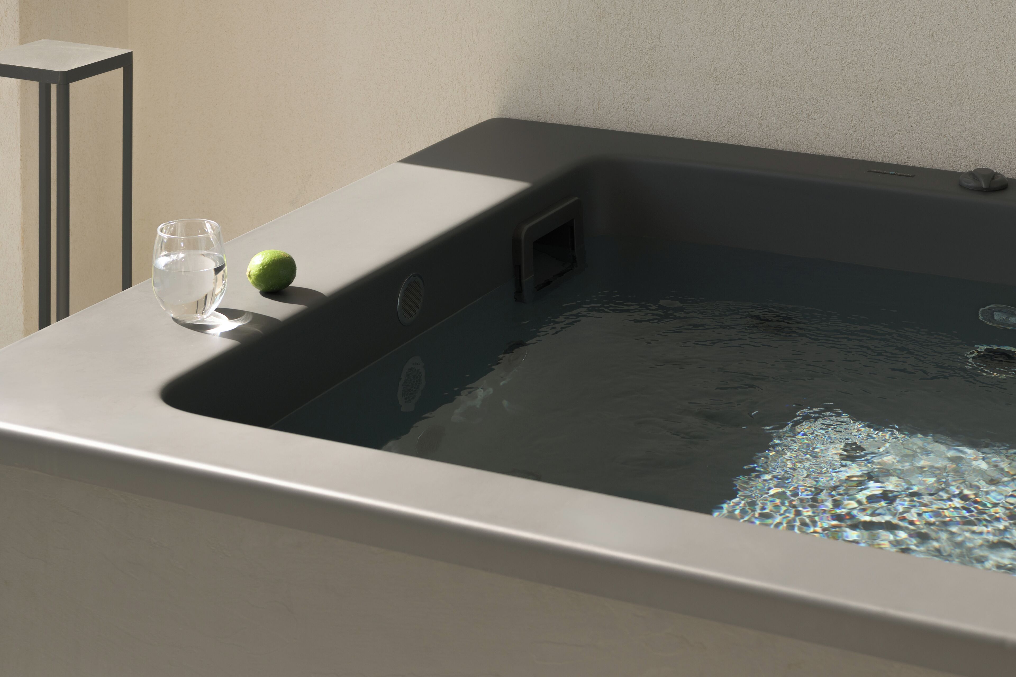 A hot tub with a glass and a fruit on the edge.
