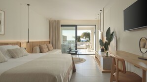 Ett modernt hotellrum med en stor säng, ett skrivbord, en TV och en balkong med utsikt över havet.
