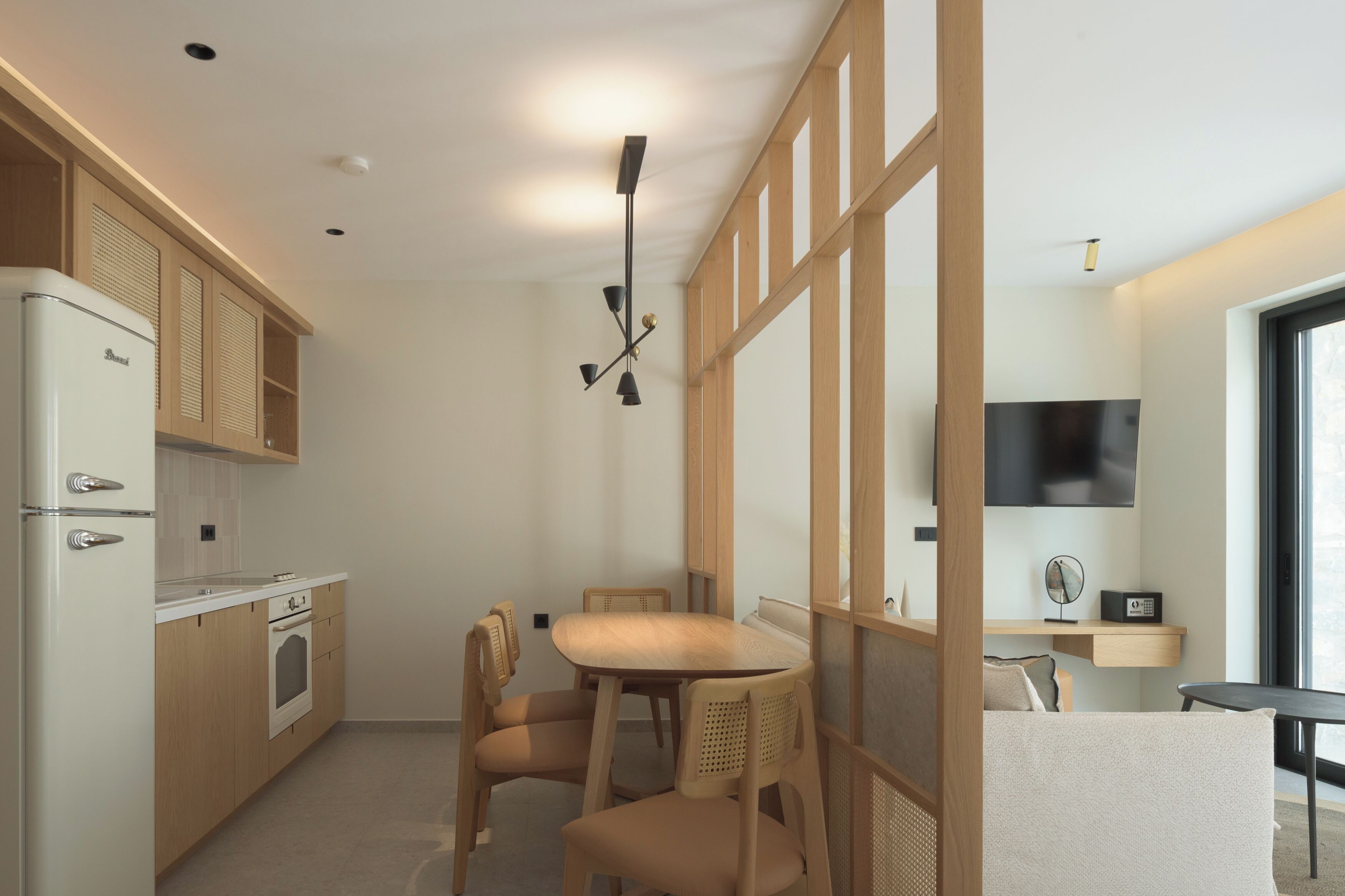 A modern kitchen with wooden cabinets, a built-in oven, and a dining area with a table and chairs.