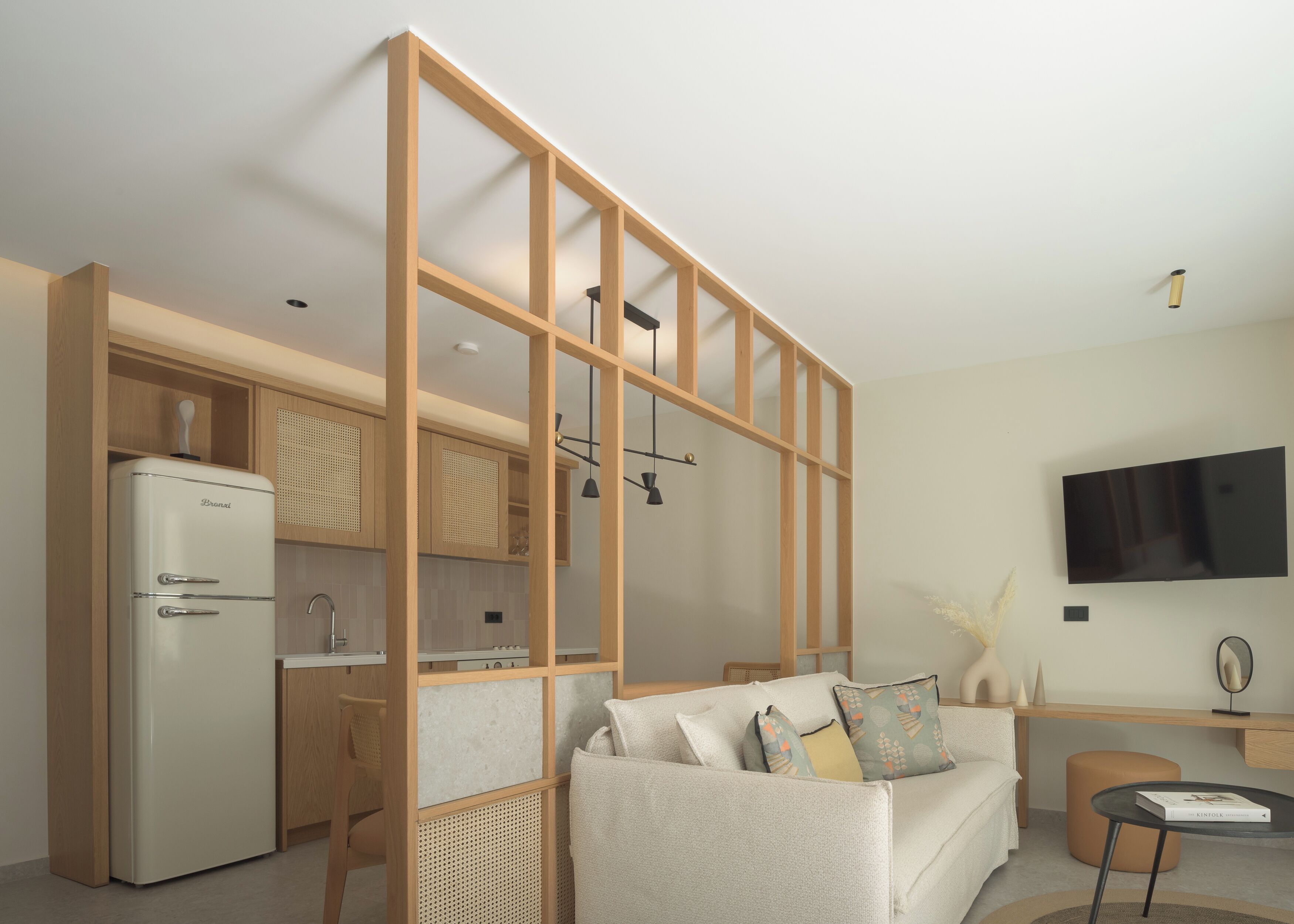 A modern living space with a kitchen, a sofa, a TV, and a small table.