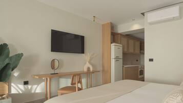 A modern hotel room with a bed, a desk, a chair, a flat-screen TV, a refrigerator, and a kitchenette.