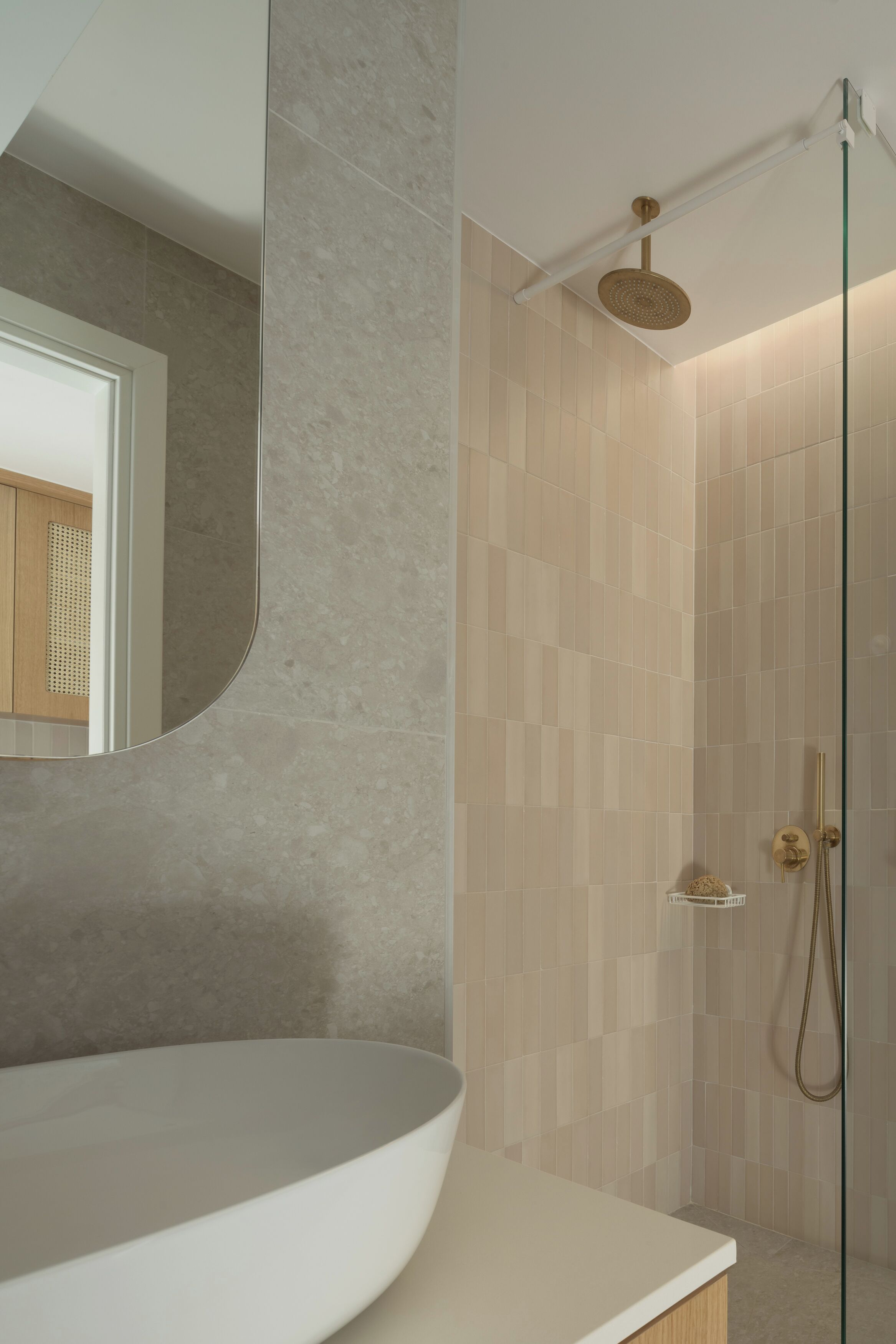 A modern bathroom with a large white sink, a glass shower enclosure, and a wall-mounted mirror.