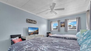 A bedroom with two beds, a ceiling fan, a TV, and a window with curtains. - New Listing!  Perfect retreat bayside off 28th St with a Pool! (Ocean City)