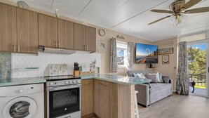 A modern kitchen with wooden cabinets, a built-in oven, and a washing machine. - New Listing!  Perfect retreat bayside off 28th St with a Pool! (Ocean City)