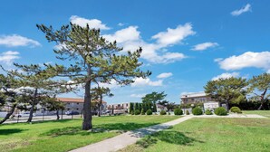 A park with a paved walkway, green grass, and trees. - New Listing!  Perfect retreat bayside off 28th St with a Pool! (Ocean City)