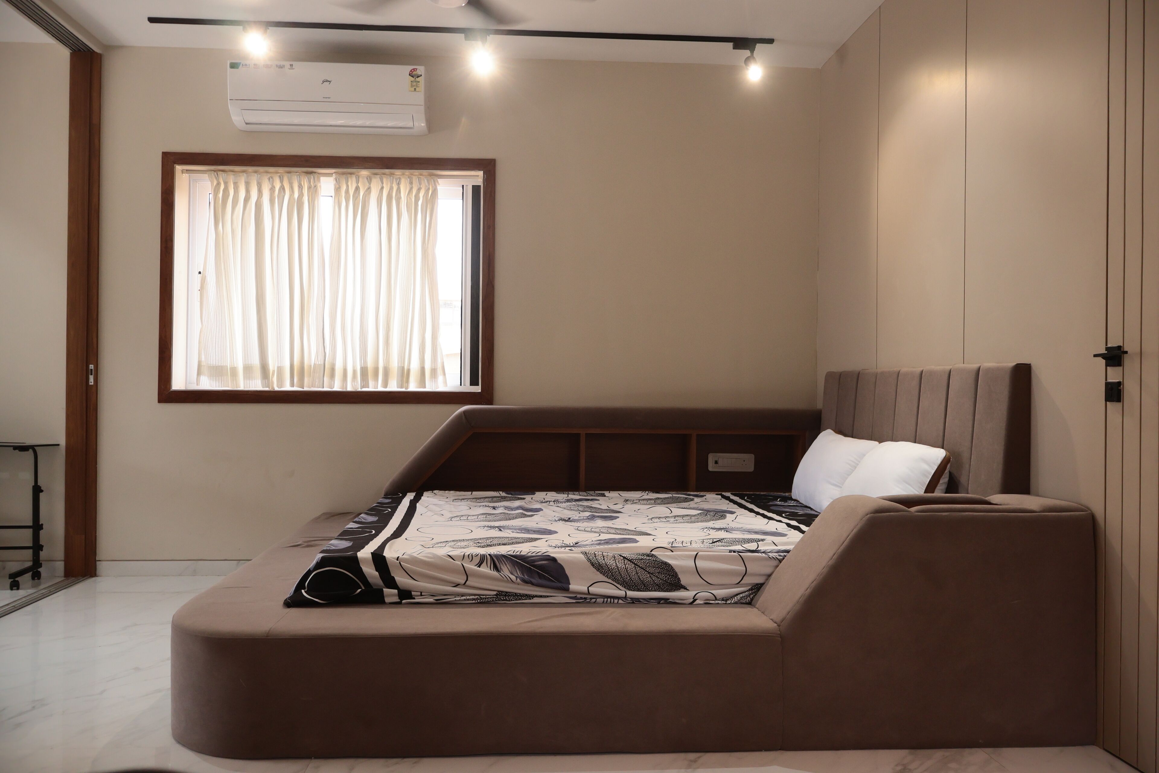 Un dormitorio con cama, ventana con cortinas, aire acondicionado y mesita de noche.