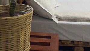A bed with white bedding, a wooden headboard, and a potted plant on a wicker chair. - Kilimanjaro sons Homestay (Moshi)