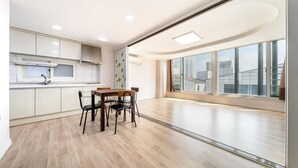 Eine moderne Küche mit weißen Schränken, einem Holztisch und einem großen Fenster mit Blick auf die Stadt.