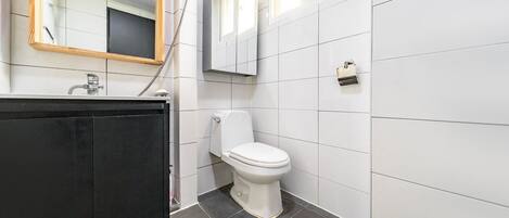 A modern bathroom with a black vanity, white toilet, and tiled walls.