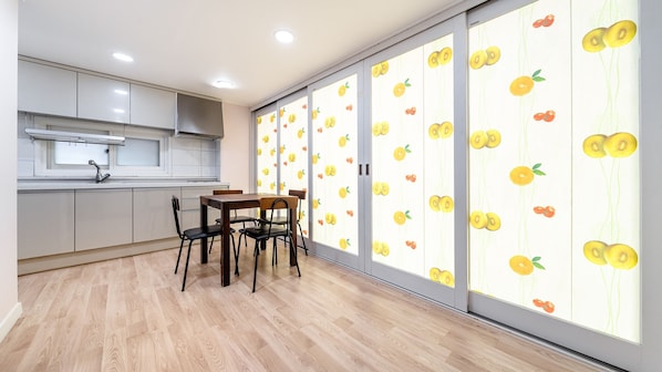 Una cucina moderna con zona pranzo, caratterizzata da un'ampia finestra con decorazioni a motivi di frutta.