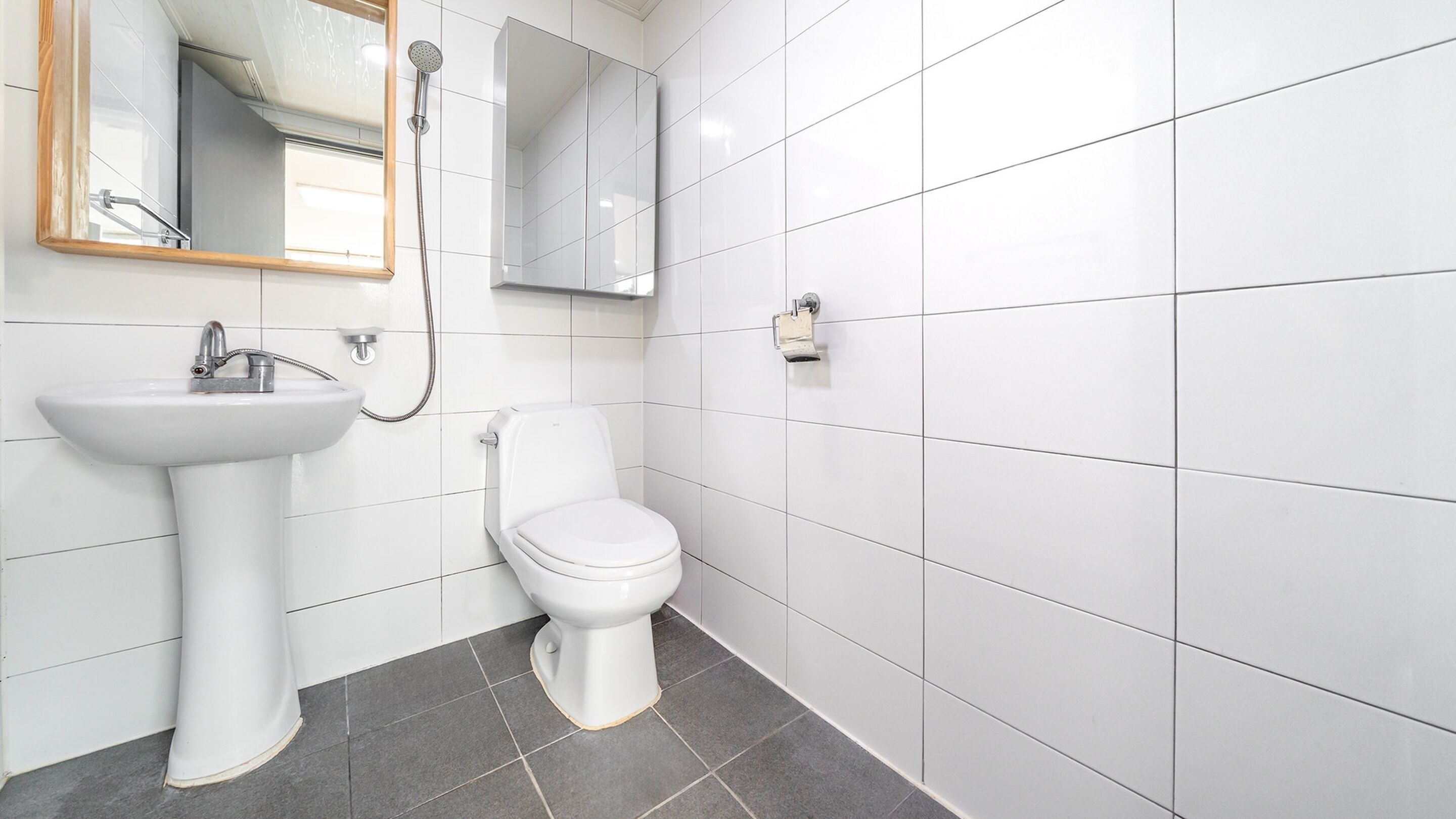 A bathroom with a white sink, toilet, and shower.