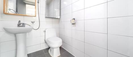 A bathroom with a white sink, toilet, and shower.