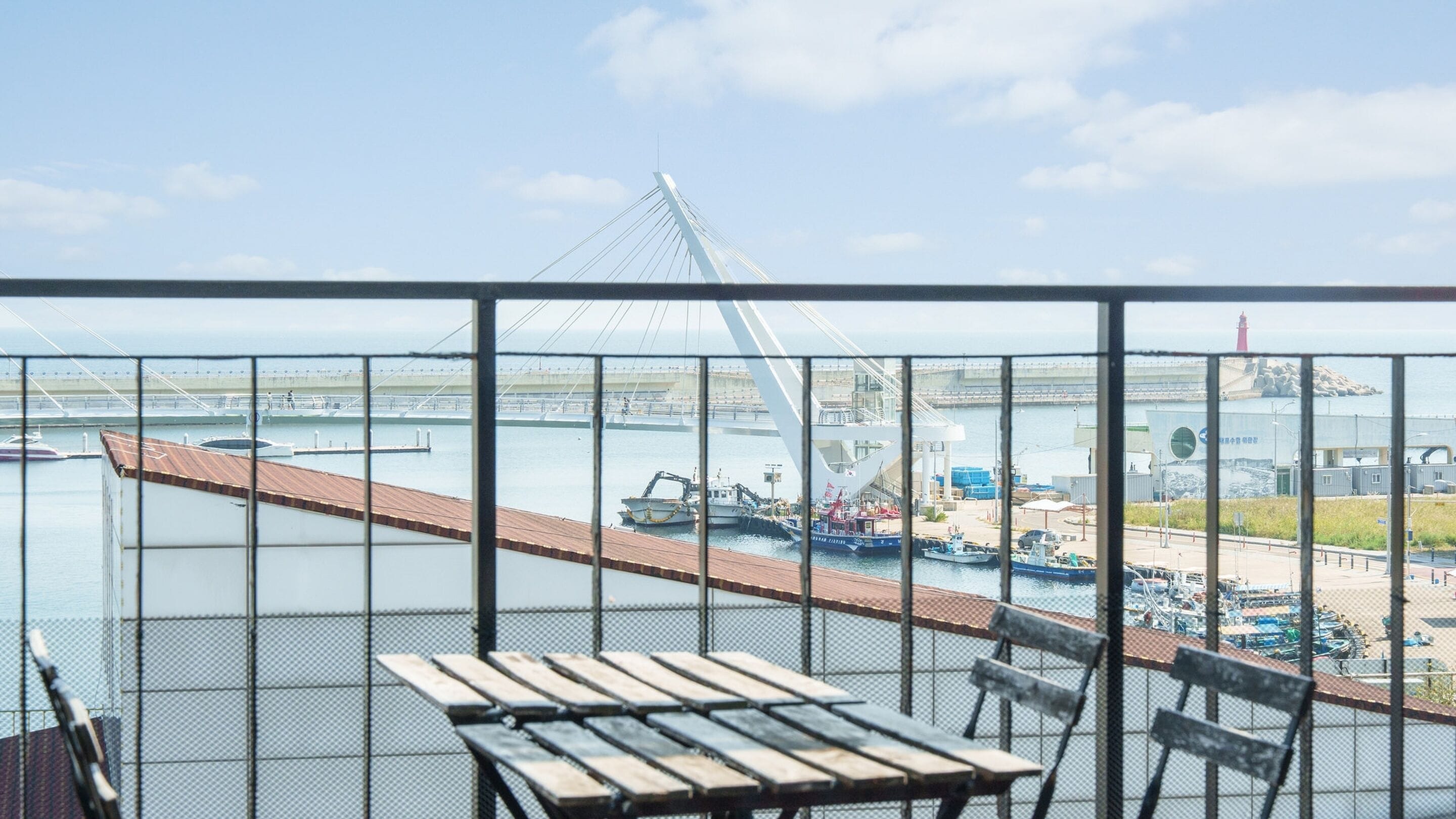 Varanda com vista para uma ponte, barcos e edifícios industriais.