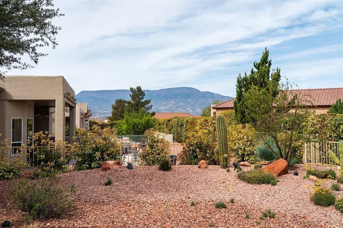 Un quartier résidentiel avec une allée en gravier, des cactus et une montagne en arrière-plan.