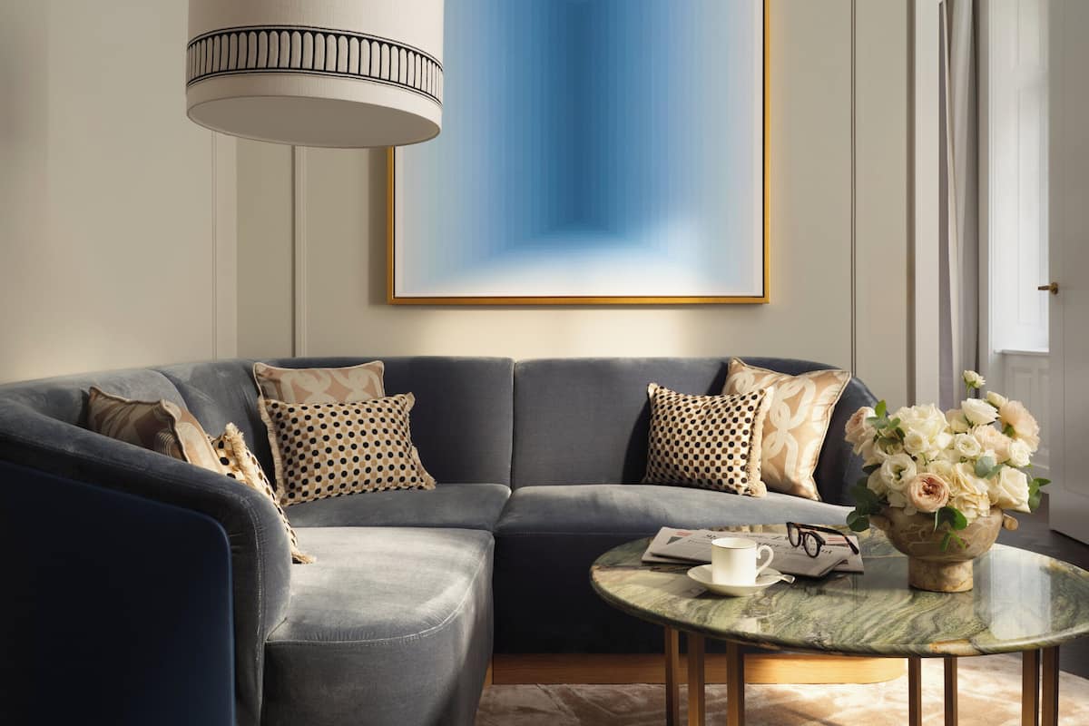 Ein modernes Wohnzimmer mit einem Ecksofa, einem runden Couchtisch und einem großen abstrakten Gemälde an der Wand.