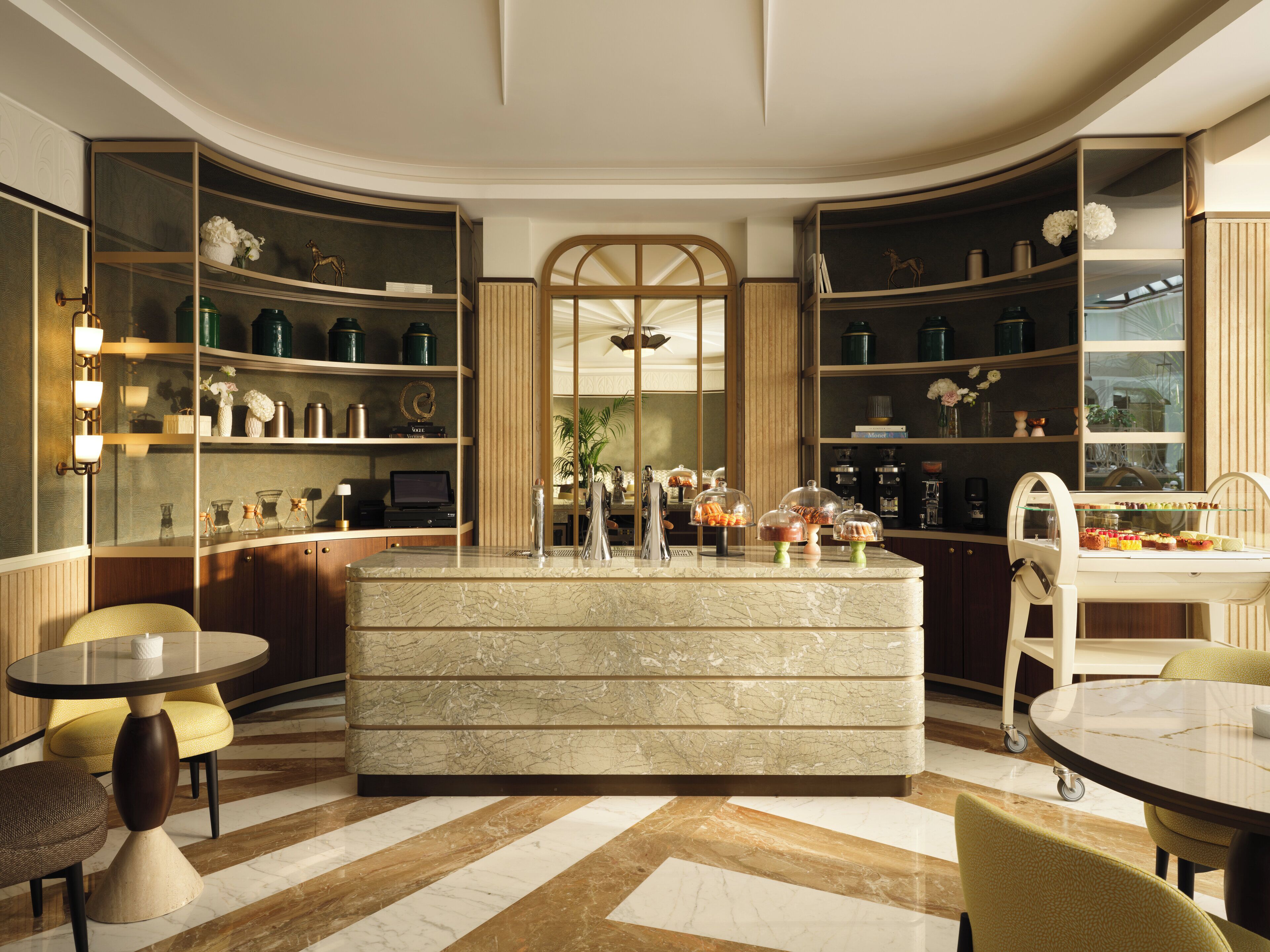 A modern kitchen with marble countertops, built-in shelves, and a central island.