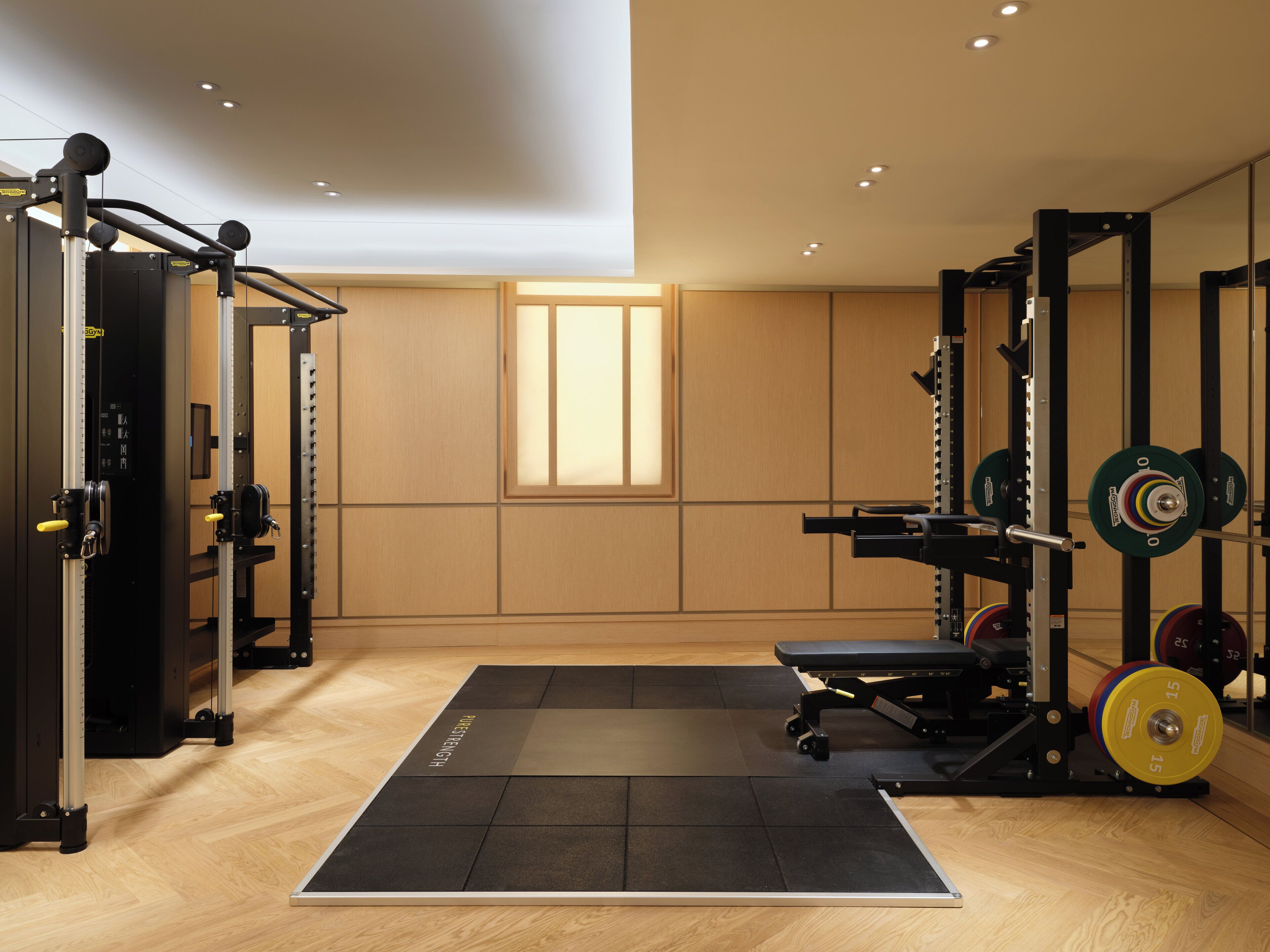 Un gimnasio con equipo de levantamiento de pesas, una barra de dominadas y una banca.