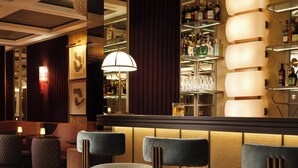 A bar area with bar stools, a mirrored wall, and a shelf with bottles. - Mandarin Oriental, Vienna (Vienna)