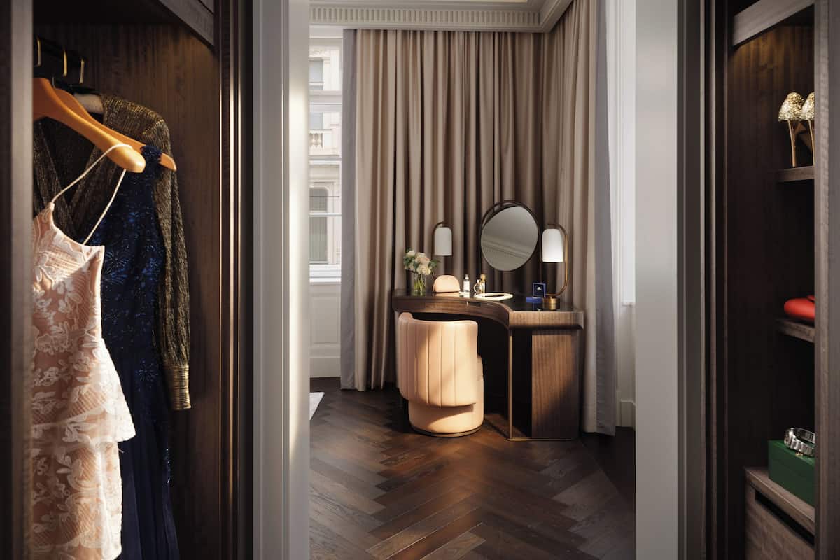 Ein Hotelzimmer mit einem Holzschrank, einem Schminktisch mit Spiegel und einem Parkettboden mit Fischgrätenmuster.