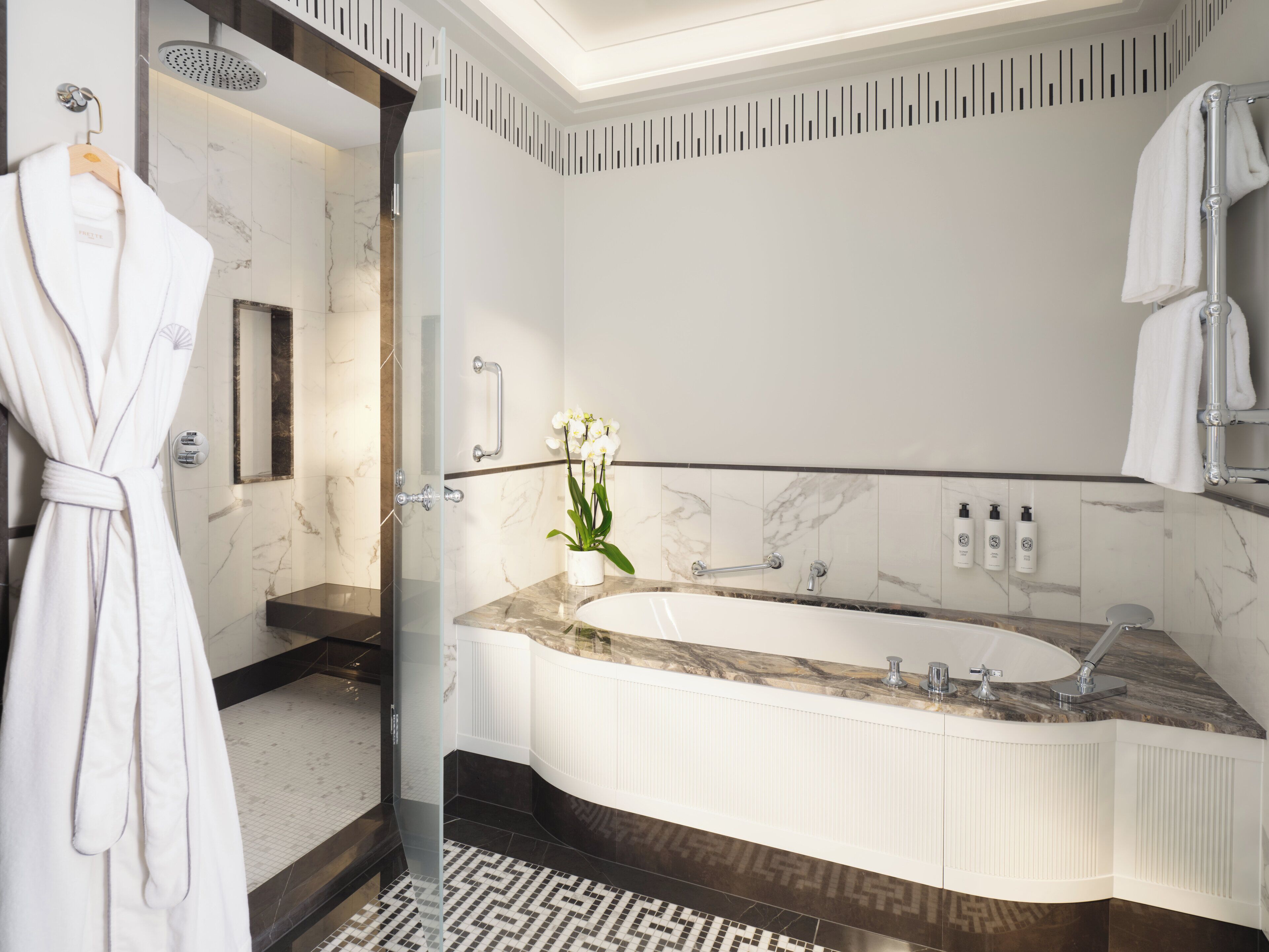 A modern bathroom with a large bathtub, a glass shower enclosure, and a marble vanity.