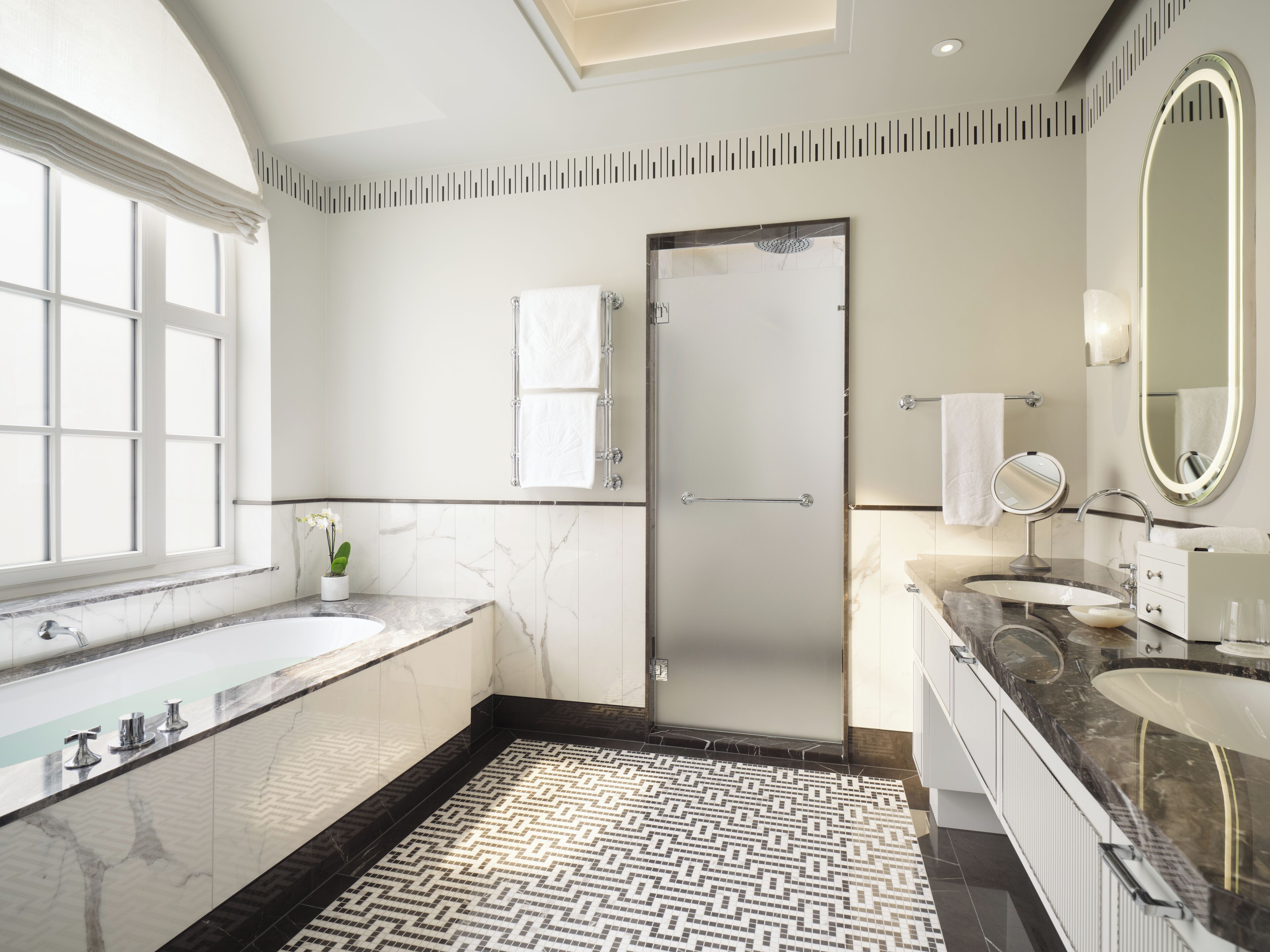 A modern bathroom with a large bathtub, a shower, and a vanity with a mirror.
