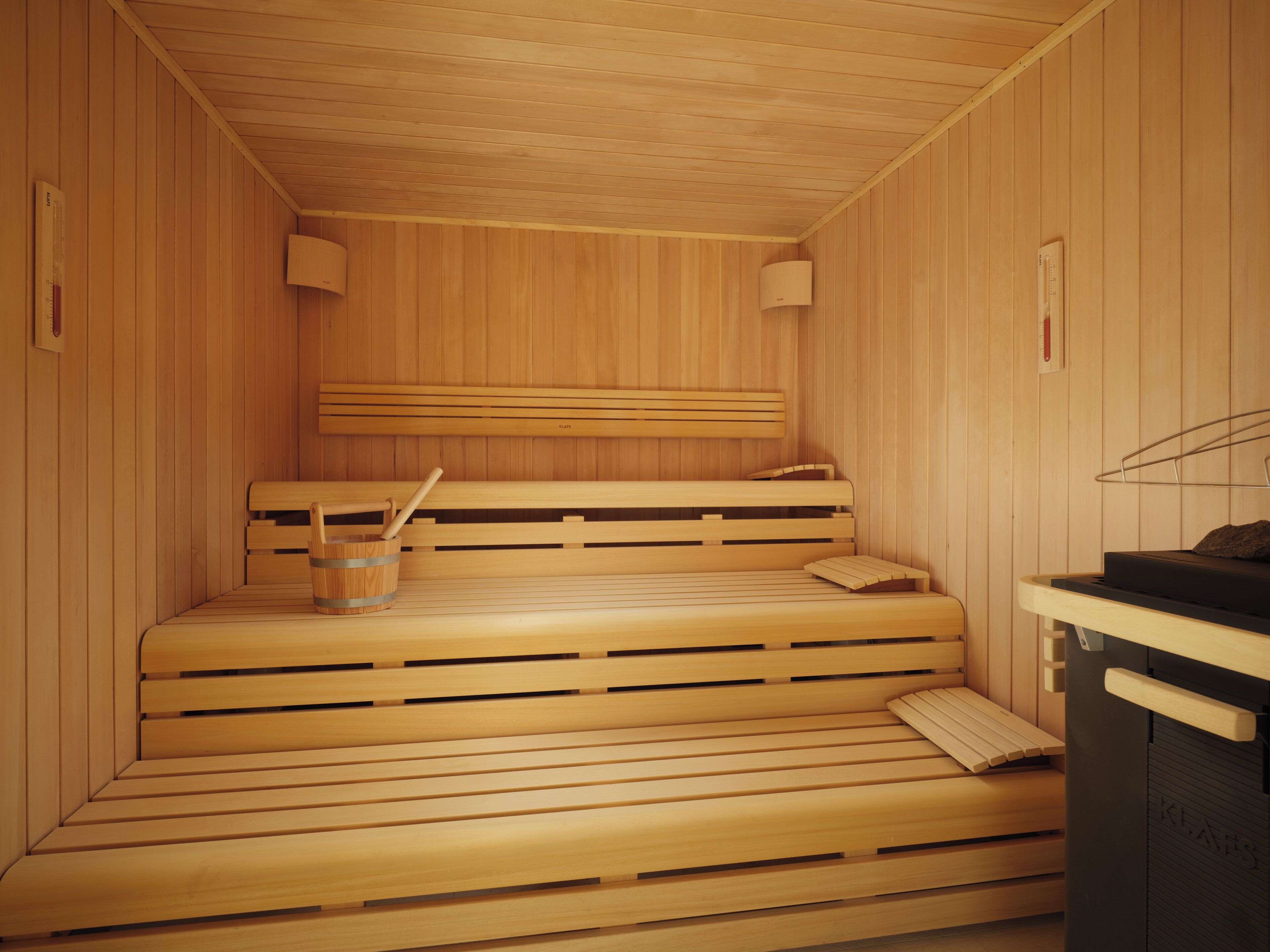 Una sauna de madera con bancos y un cubo de madera.