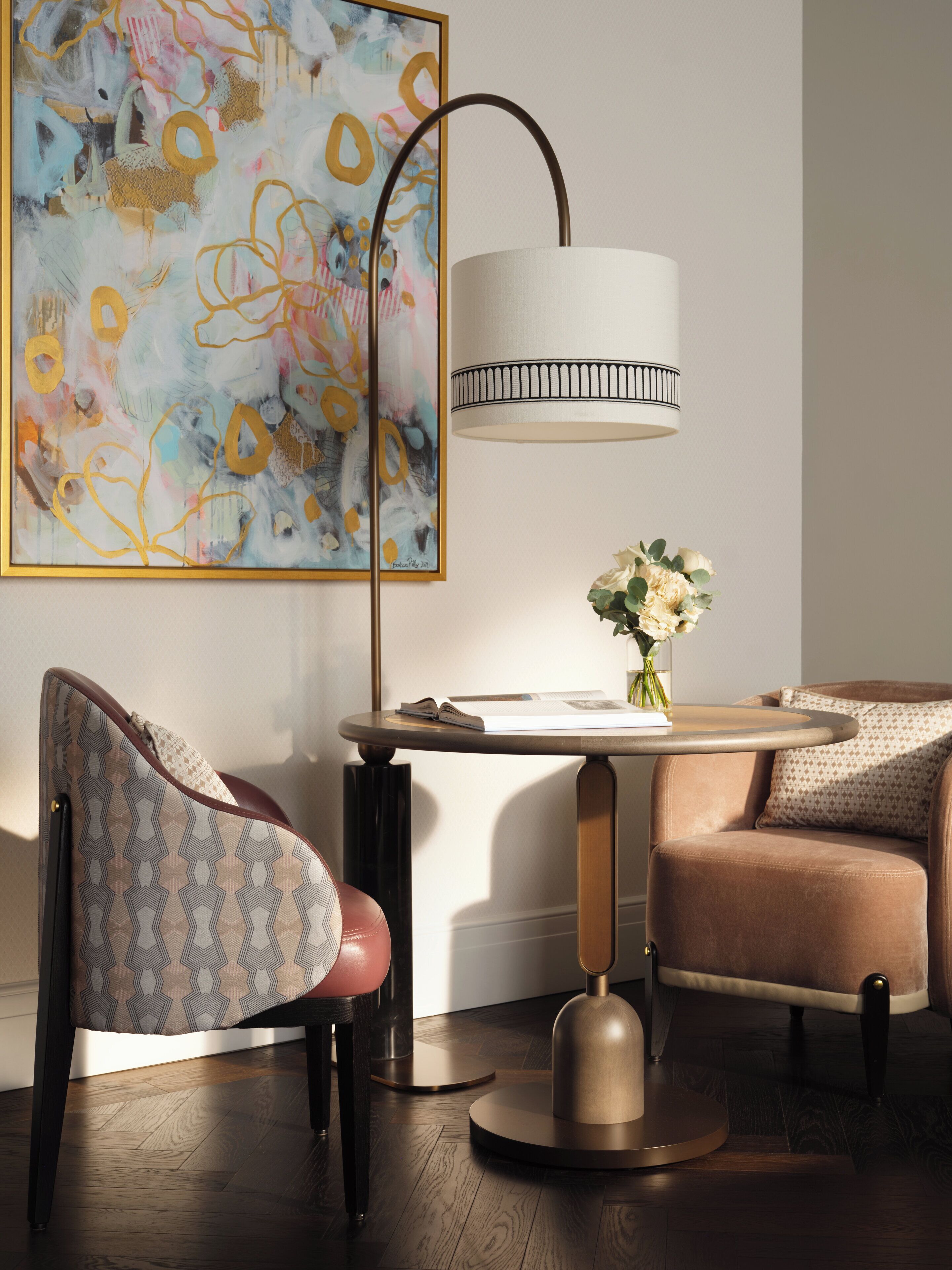 A modern room with a round table, two chairs, a floor lamp, and a large abstract painting on the wall.