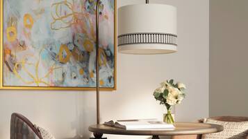 A modern room with a round table, two chairs, a floor lamp, and a large abstract painting on the wall.