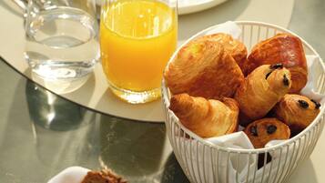 Une table avec des croissants, un verre de jus d’orange et une assiette de nourriture.