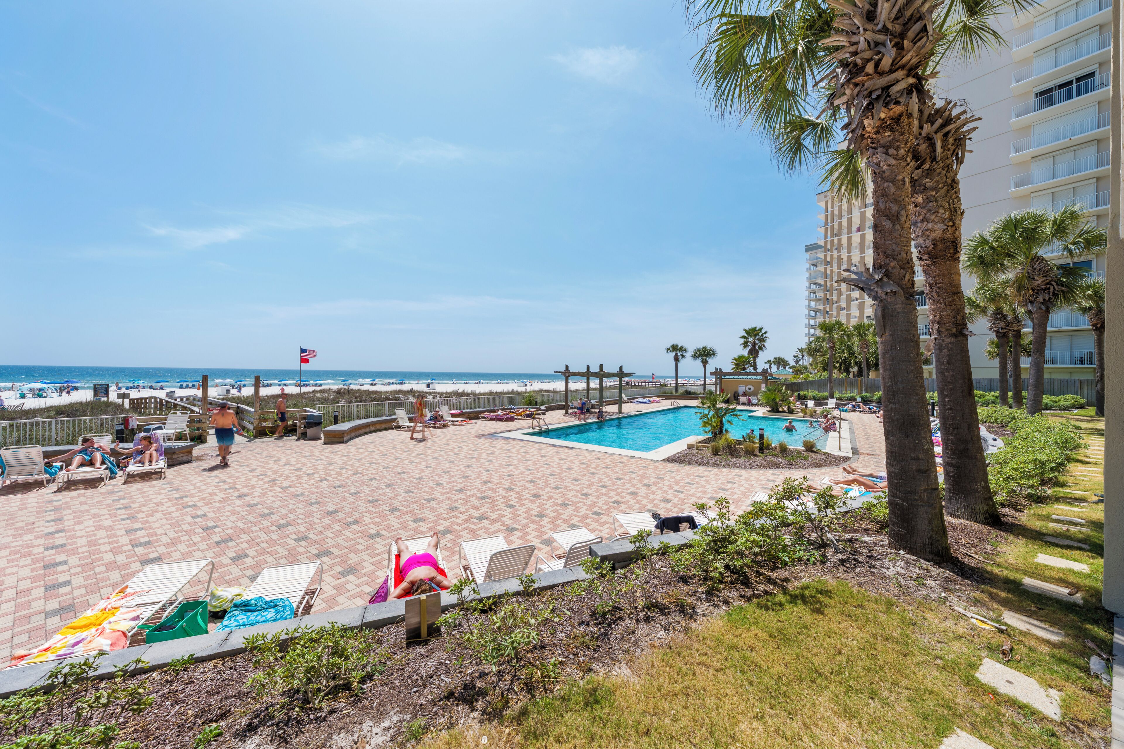 Un espace aménagé au bord de la piscine, avec des chaises longues, une petite piscine et une vue sur la plage et l’océan.