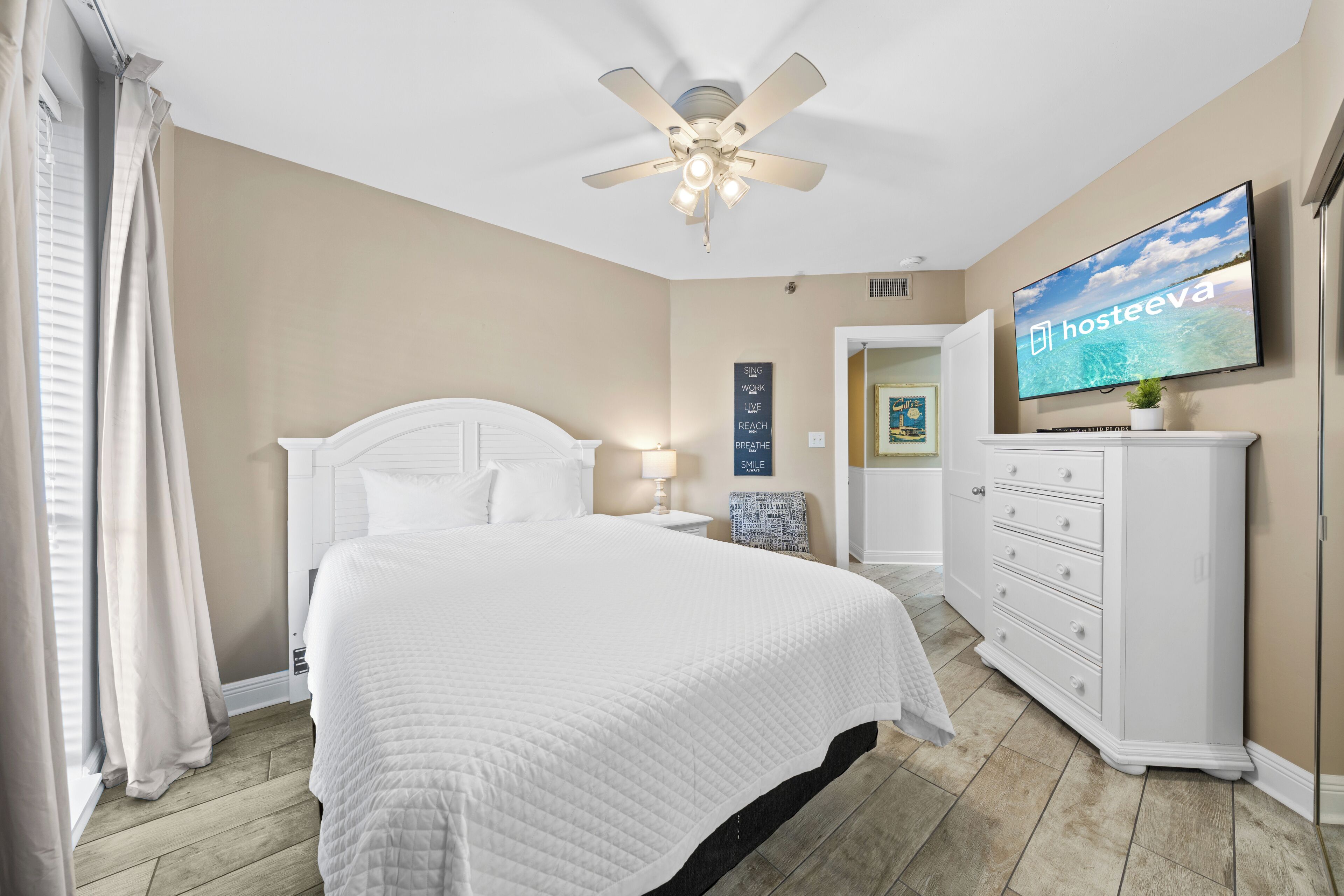 Una habitación de hotel con cama, ventilador de techo, televisor y cómoda.