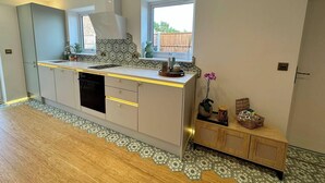 Una cocina moderna con una isla central, electrodomésticos integrados y un ventanal que proporciona luz natural.