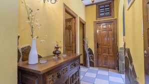 A hallway with a wooden bench, a white vase with flowers, and a checkered floor.