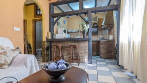 A cozy living room with a sofa and a table with decorative bowls. A kitchen is visible in the background with a rustic design.