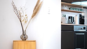 A modern kitchen with a wooden sideboard, a vase with dried plants, and a kitchen island.