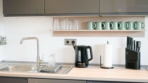 A kitchen with a sink, faucet, kettle, and knife block.
