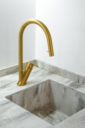 Un baño con grifo dorado e lavabo de mármol.